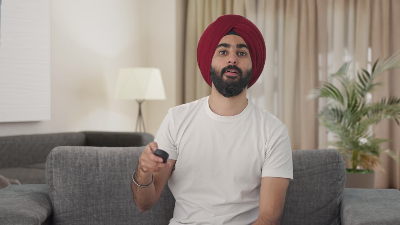 Glad indisk sikhisk mand ser tv