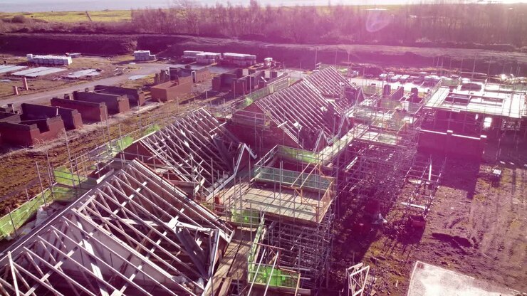 Unfinished waterfront housing property development scaffolding framework on builders construction site aerial view