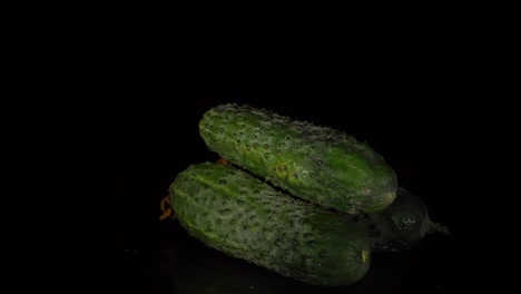los pepinos de piel verde giran sobre un fondo negro.