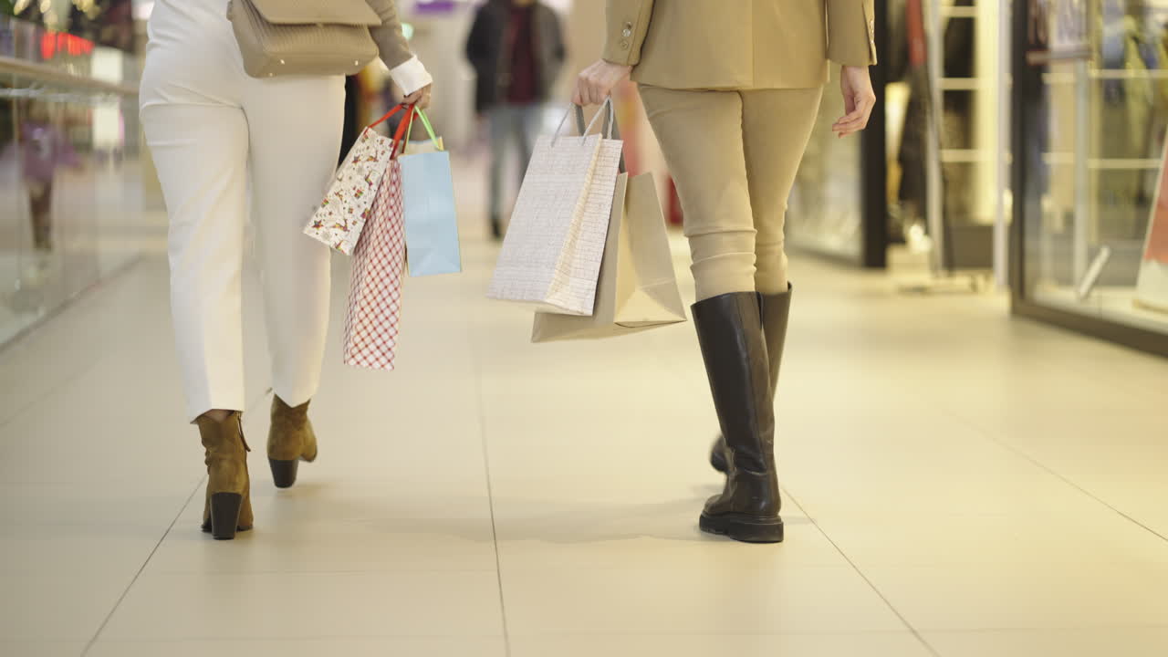 Two women walking with shopping bags in a mall