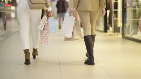 two women walking with shopping bags in a mall