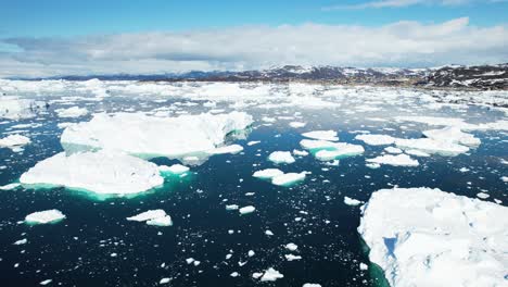 pieces of melting iceberg float in deep blue ocean, aerial view