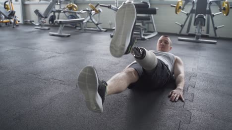 athlete with prosthetic leg doing ab exercises on the gym floor