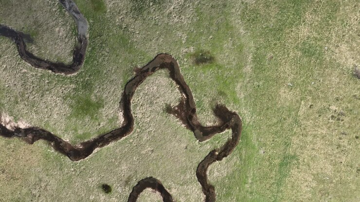Flight over a winding mountain stream with clear water on a sunny spring day