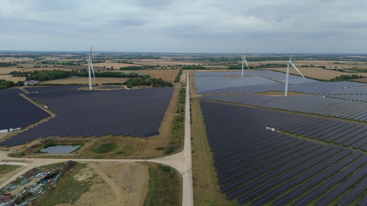 Aerial drone footage over large power station with solar panels and turbines generating green electricity Raunds England UK