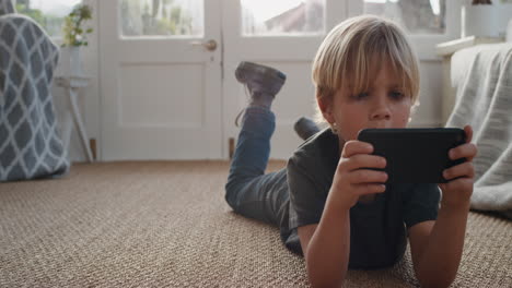 little boy using smartphone playing games relaxing lying on floor at home child browsing online with mobile phone technology anti social addiction concept 4k footage