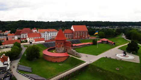 tomada de avión no tripulado del histórico castillo de ladrillo rojo de kaunas con bandera ucraniana en el casco antiguo de kaunas, lituania, toma de paralaje