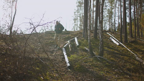 Ruhiges-Wandern-Im-Wald-An-Einem-Herbsttag.-Ein-Mann-Mittleren-Alters-Steigt-Mit-Einem-Rucksack-Beim-Camping-Vom-Hang-Ab