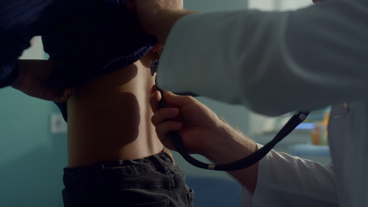 의사가 폐를 듣고 십대 소녀가 의사 검사에서 스테토스코프를 사용합니다.