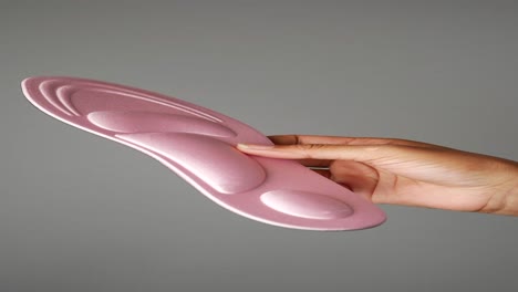 woman's hand holding pink shoe insoles