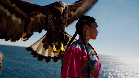 woman in traditional dress with eagle, coastal scenery