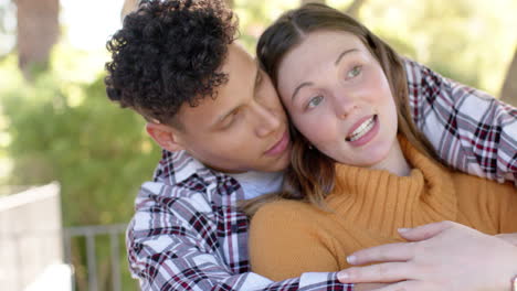 Happy-diverse-couple-standing-on-balcony-and-embracing-at-home,-in-slow-motion