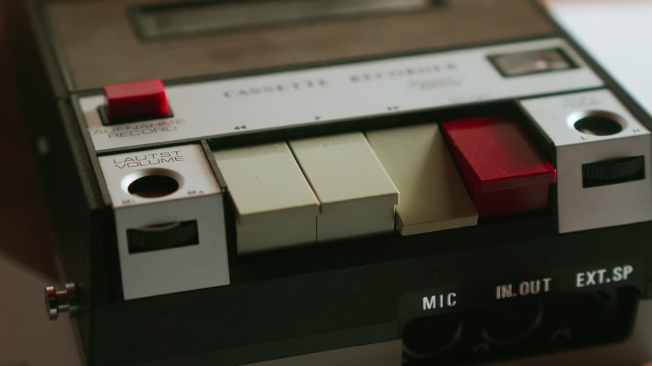 Close-up van ingedrukte knoppen van een analoge cassetterecorder, retro scène geschikt voor misdaadthema's, politieonderzoeken en beelden van interviewopnames.