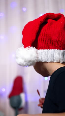cute boy in santa cap sits on the floor. kid stands up and walks to christmas tree. low angle view. vertical video