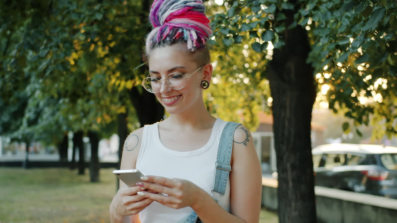 una mujer joven enviando mensajes de texto por teléfono en el parque.