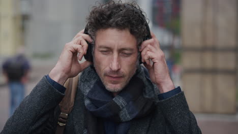 portrait-attractive-mature-businessman-puts-on-headphones-listening-to-music-enjoying-relaxed-urban-commuting-lifestyle-slow-motion