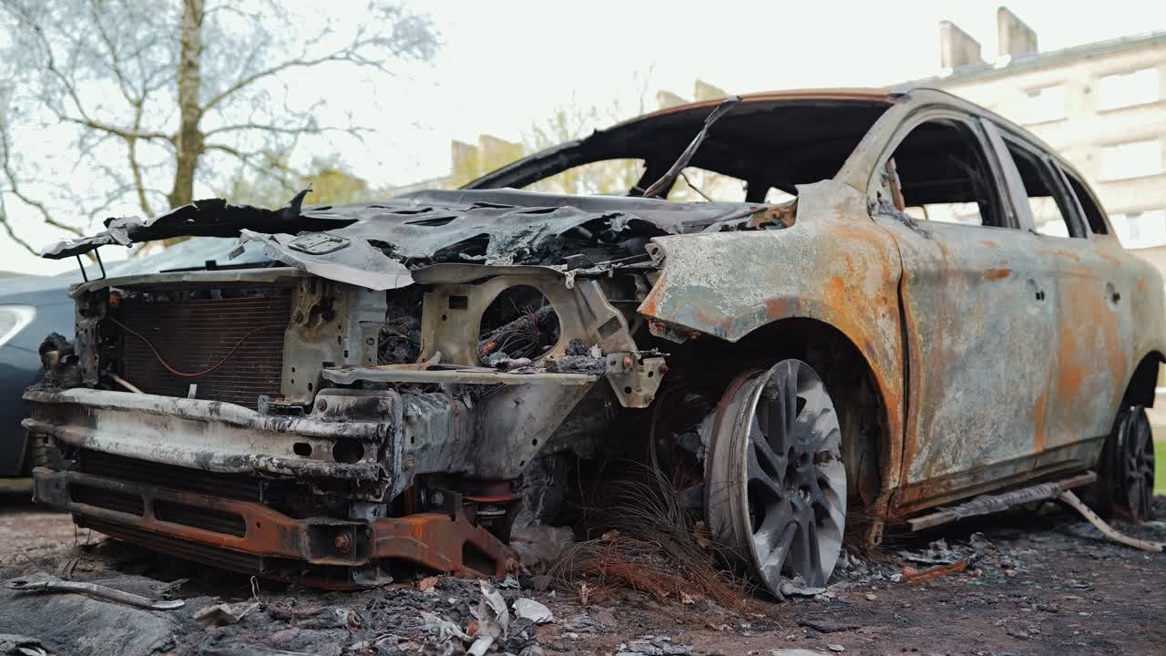 Burned vehicle wreck symbolizes war destruction, lost transport and instability