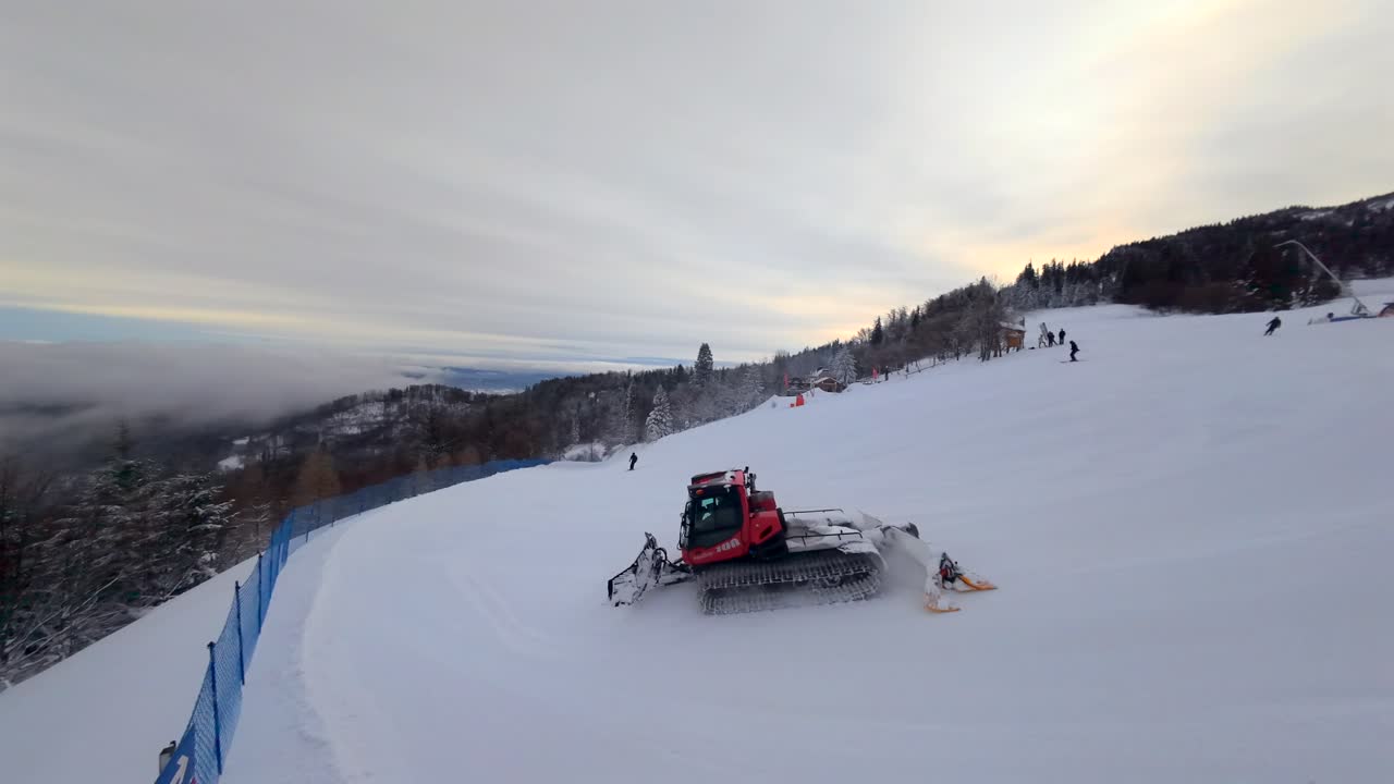 Inseguimento dinamico con drone in prima persona di un gatto delle nevi che prepara le piste da sci a Jaworzyna, a Szczyrk, sui Monti Beschidi polacchi. Filmato invernale cinematografico con paesaggi montani, neve fresca e macchinari del resort