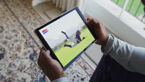 compuesto de un hombre sentado en casa, viendo un juego de béisbol en la tableta