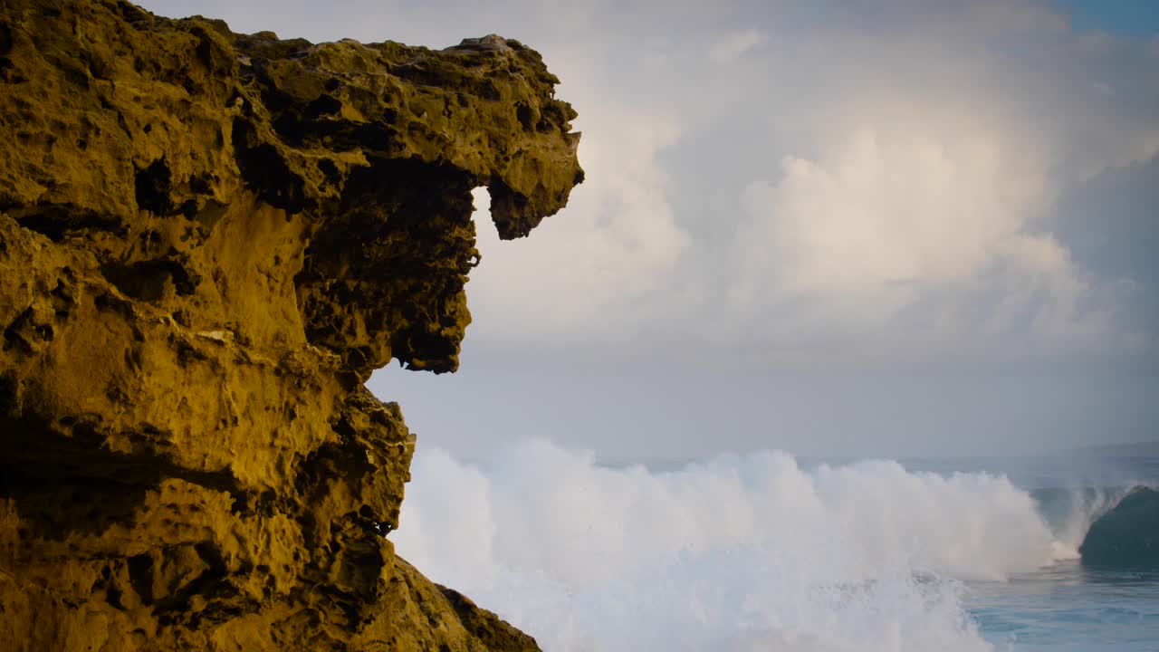 las olas azules llegan a la costa de hawaii a cámara lenta y rompen a lo largo de una costa escarpada