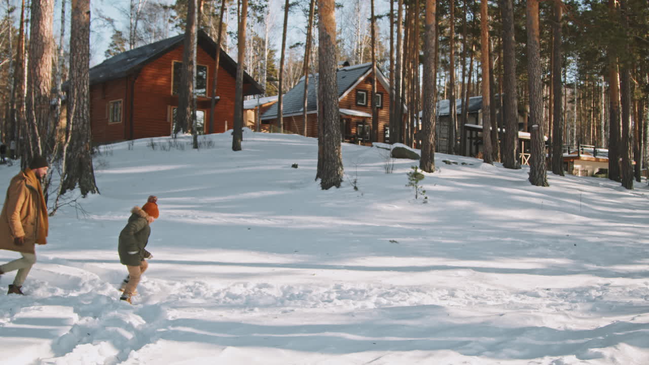 Happy Family of Three Running in Snow in Countryside