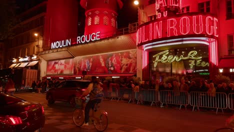 moulin rouge cabaret illuminated with red lights at night in paris, france. - tilt up shot