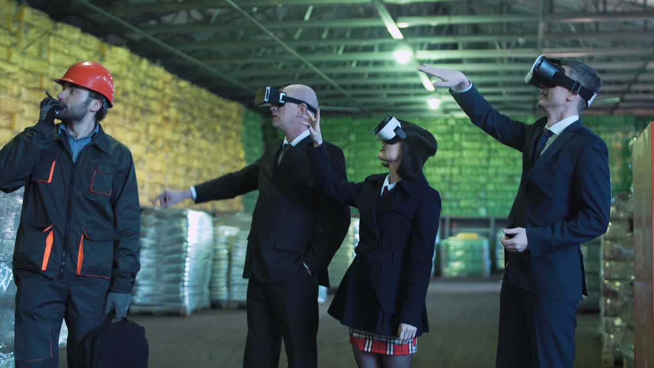 Business people and a worker using VR headsets in an industrial warehouse