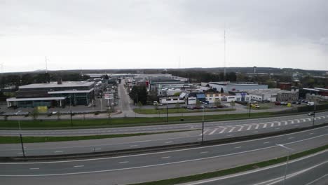 a drone rises over the roadway overlooking businesses and a wind turbine