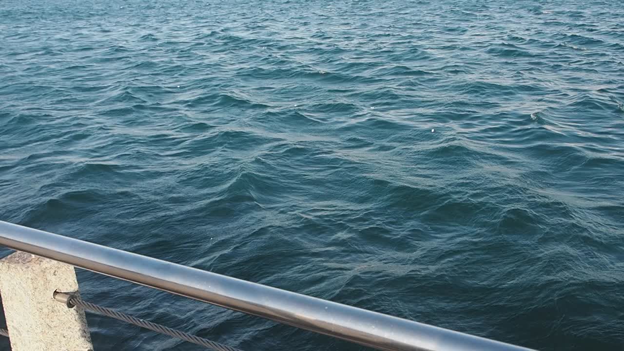 Meereswellen mit einem Geländer im Vordergrund
