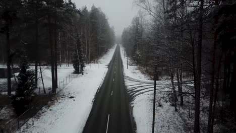 aerial drone view of empty winter road with forest on both sides