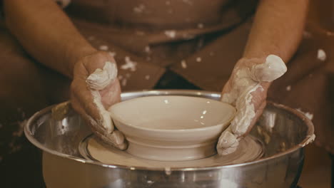 close-up view of a potter shaping a bowl on a pottery wheel