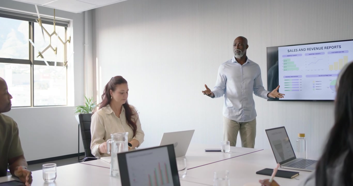 Diverse team watching African American man presenting sales data after slide in office, copy space