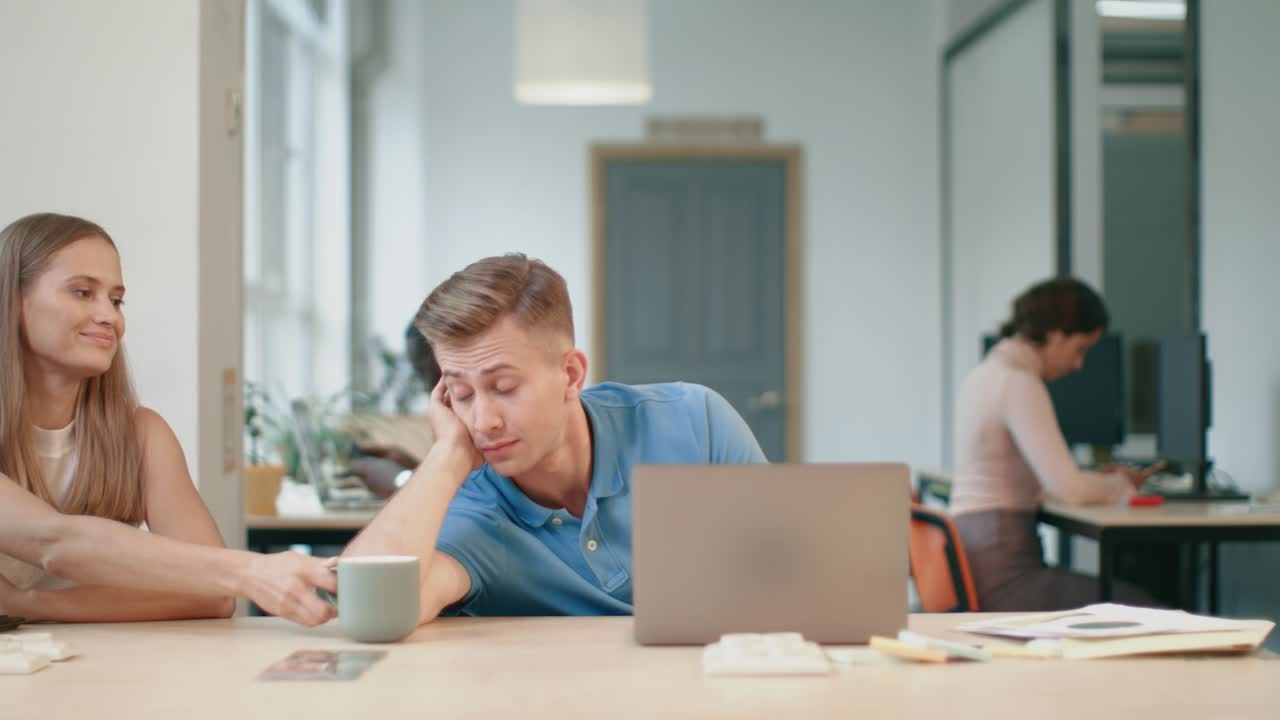 Sleepy business man laying with laptop at coworking. Young man saying thank you.