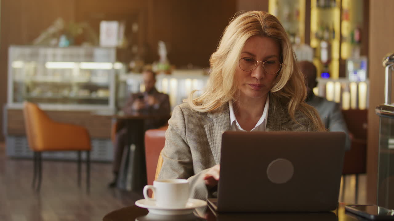 Donna d'affari concentrata che lavora al portatile in un caffè d'hotel