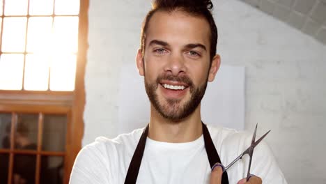 Male-hairdresser-standing-with-scissor-in-hair-salon