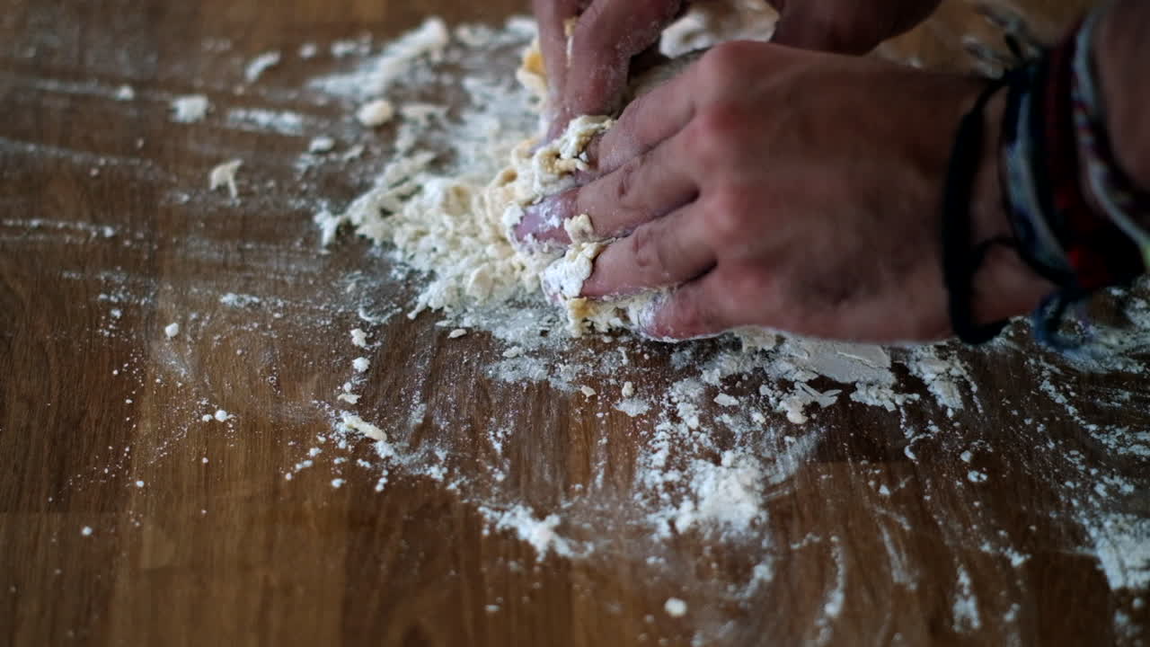 manos artesanales amasan la masa en superficie de madera para la fabricación tradicional de pasta