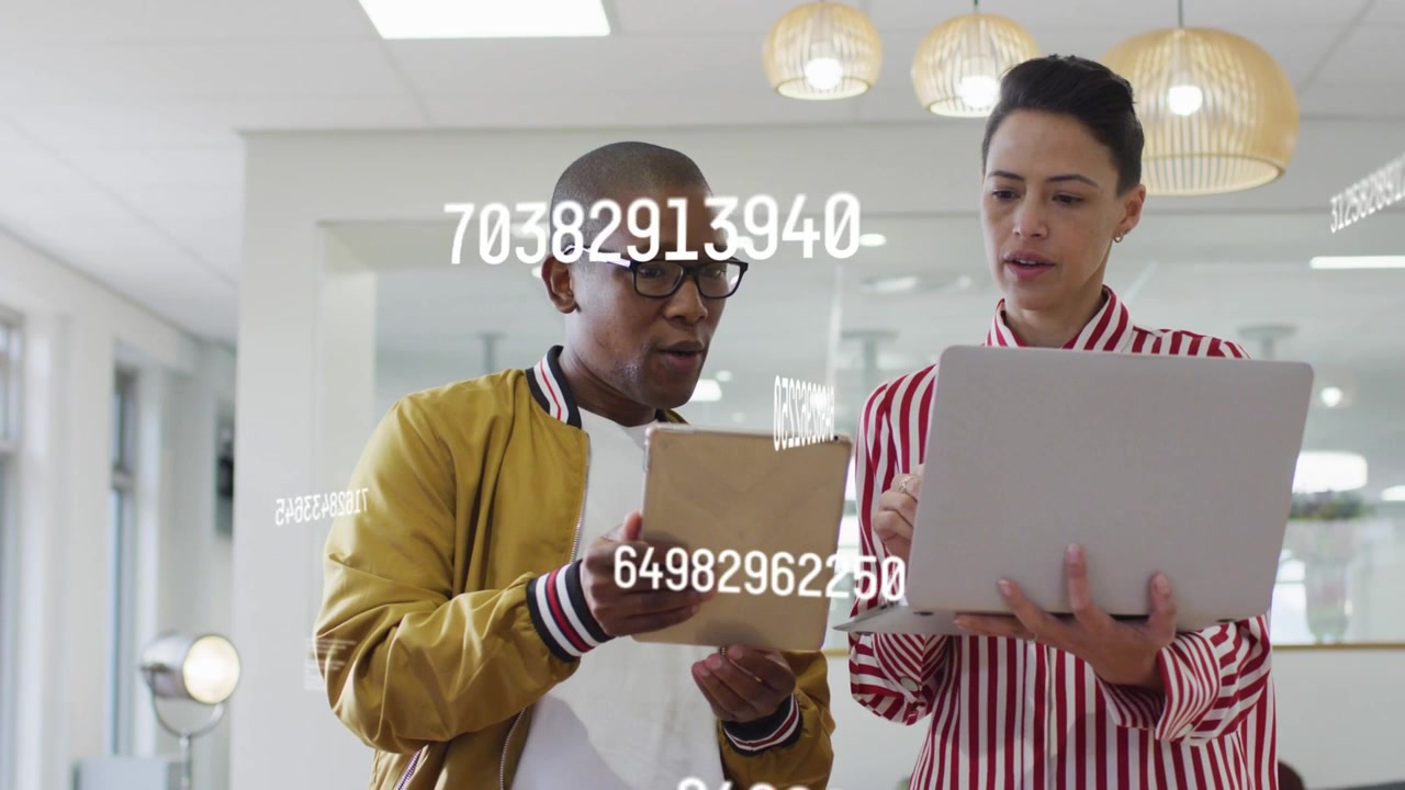 Man pointing tablet, woman leaning in, colleagues reviewing business metrics with floating numbers