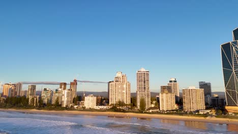 drone footage captures gold coast's skyline and beach at sunrise, highlighting modern architecture and serene ocean views