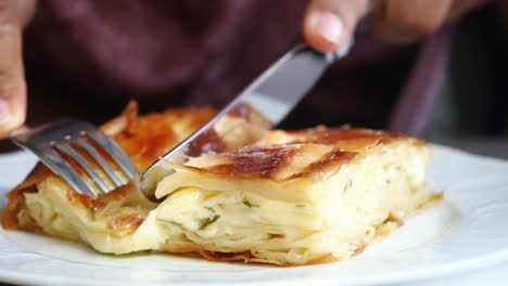 closeup of a turkish pastry called su boregi, a flaky cheesy pastry with a golden brown crust.