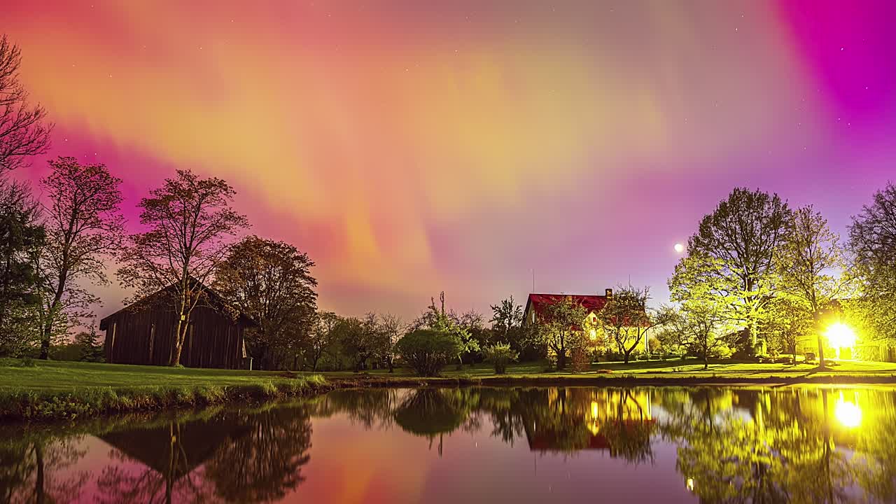 el lapso de tiempo de las luces del norte que se reflejan en un lago frente a una casa de campo