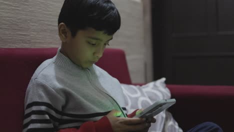 young-kid-watching-mobile-and-playing-online-game-at-home-at-night-from-different-perspective