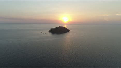 Flying-to-a-loneley-island-over-open-water-and-ocean-in-cambodia-otres-beach-near-sihanoukville-asia,-while-sunset-going-down,-scenic-orange-travel