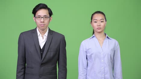young asian business couple pointing up together