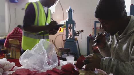 Mixed-race-man-checking-work-quality-in-factory