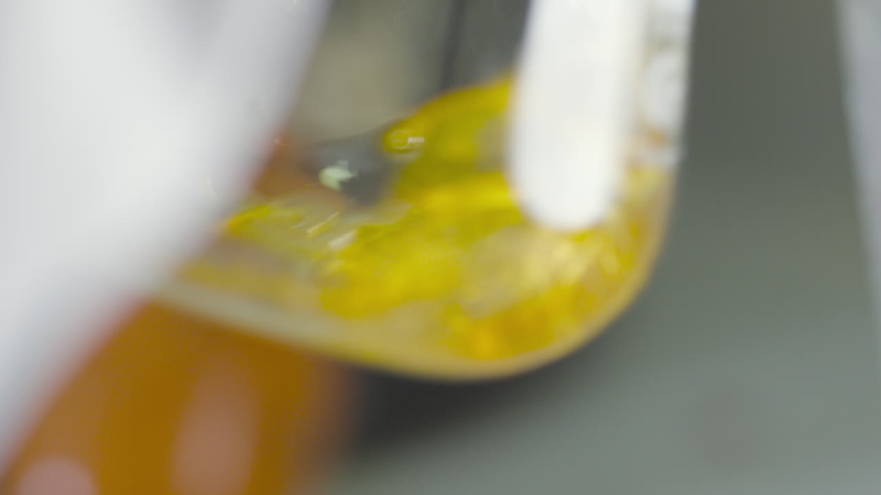 Close-up of a laboratory flask with a liquid substance swirling inside.