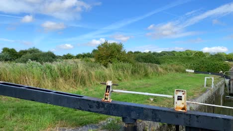 Windy-summer-day-at-the-Kennet-and-Avon-Canal-in-Devizes-England,-sunny-weather-with-blue-sky,-white-clouds-and-green-fields,-4K-shot