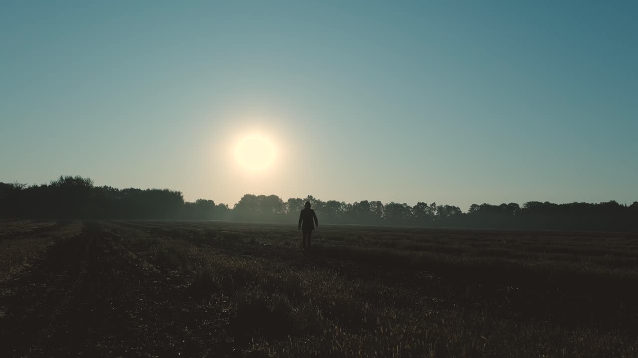 un hombre camina a través de un campo quemado al amanecer y al atardecer. silueta