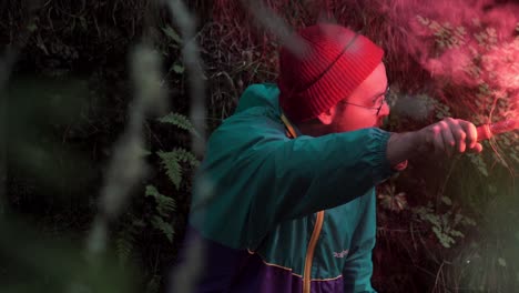 hombre sosteniendo una llamarada roja en el bosque por la noche