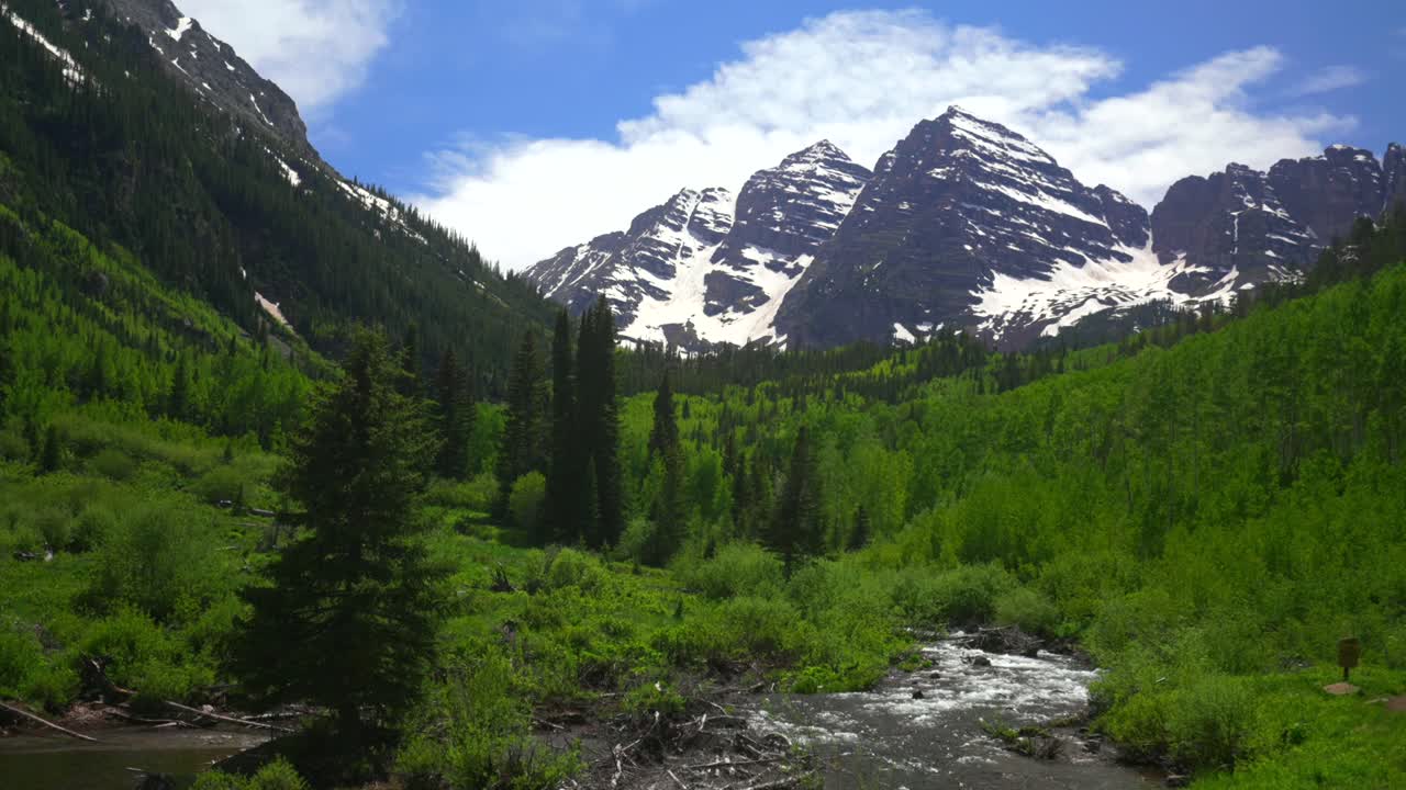 Maroon creek river Crater lake trail Maroon Bells Pyramid Peak 14er Wilderness morning sunny blue sky clouds Aspen Snowmass Colorado Elk Mountains Range White River National Forest static shot