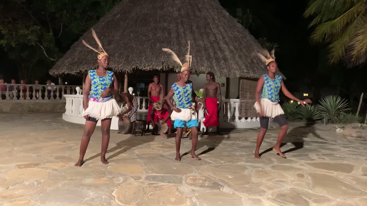 Female black dancers entertaining guests with traditional cultural dance performance. Ethnic dancing before hut at hotel at night. Evening dances entertaining guests to the beat of drums.